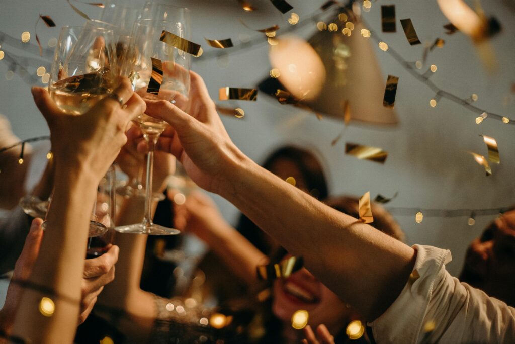 pexels-photo-3171837-3171837 A lively indoor party scene with people toasting champagne glasses amid confetti and warm lights.
